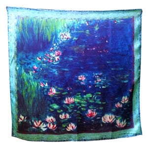 Peut inclure: Foulard carré avec un motif de nénuphars. Le foulard présente un fond bleu foncé avec des nénuphars roses et blancs et des nénuphars verts. La bordure est vert turquoise clair.