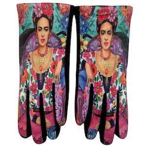 Peut inclure: Une paire de mitaines de cuisine avec une impression vibrante d'un portrait de Frida Kahlo. Les mitaines ont un poignet noir et un motif floral coloré sur fond blanc. Le portrait comprend une coiffe florale et des bijoux.