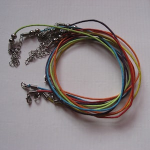 Op de afbeelding: Een set kleurrijke koordsnoeren met zilveren sluitingen en kralen. De koorden zijn in tinten rood, oranje, geel, groen, blauw en paars.
