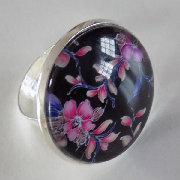 Bague ronde ajustable argent ,cabochon en verre motif fleurs roses sur fond noir.