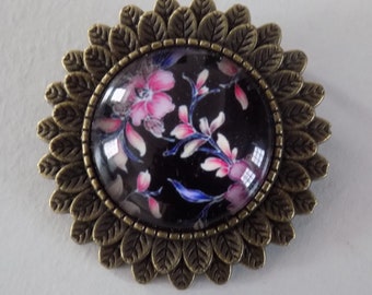 Broche bronze , décor feuilles , cabochon en verre motif fleurs coloris rose sur fond noir.