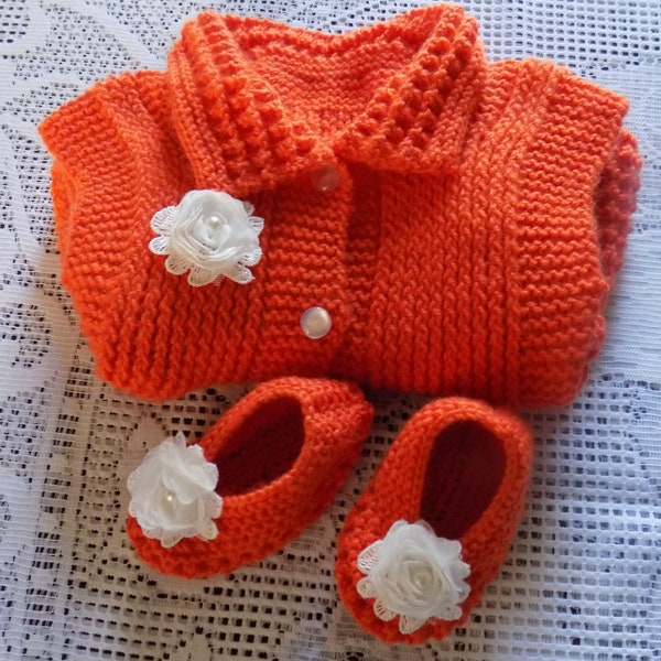 Ensemble robe et chaussons  pour bébé réalisé à la main au tricot , coloris orange , fleurs blanches organza , taille 3/6 mois.