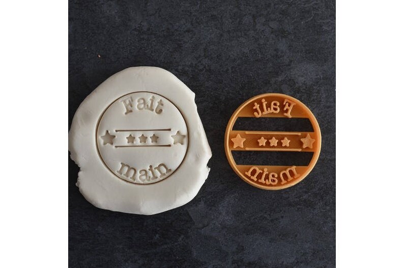 May include: Two cookie cutters, one white and one brown, with the words "fait main" and "fait maison" in French, meaning "handmade".
