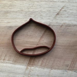 May include: A brown plastic cookie cutter shaped like a chestnut.