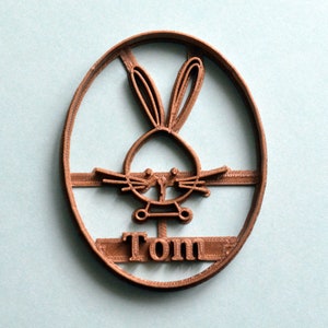 May include: Brown plastic cookie cutter shaped like a bunny rabbit with the name "Tom" underneath.