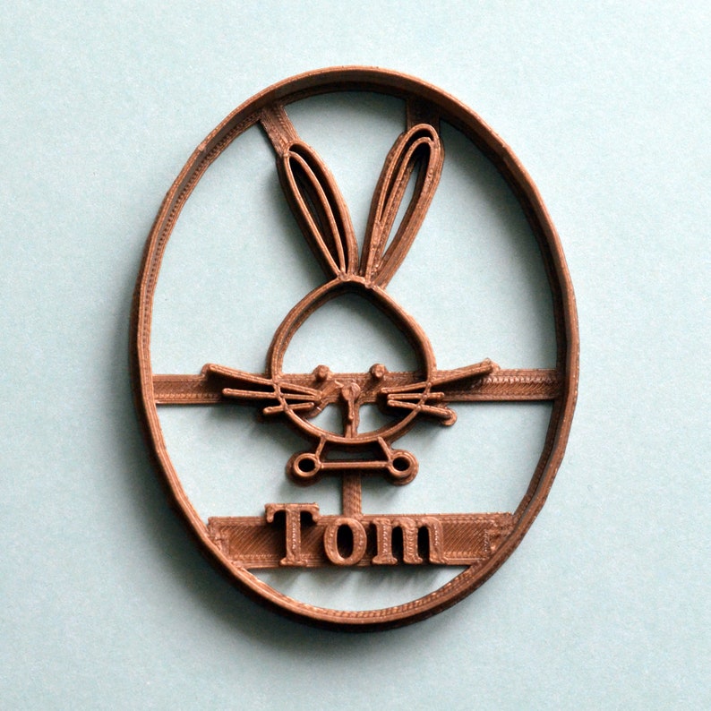May include: Brown plastic cookie cutter shaped like a bunny rabbit with the name "Tom" underneath.