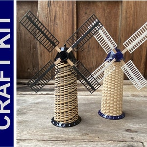 May include: Two miniature wooden windmills with black and white blades. The windmills are made of woven wood and have a blue base.