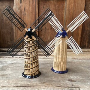 May include: Two miniature windmills with black and white blades. The windmills are made of woven wicker and have blue bases.