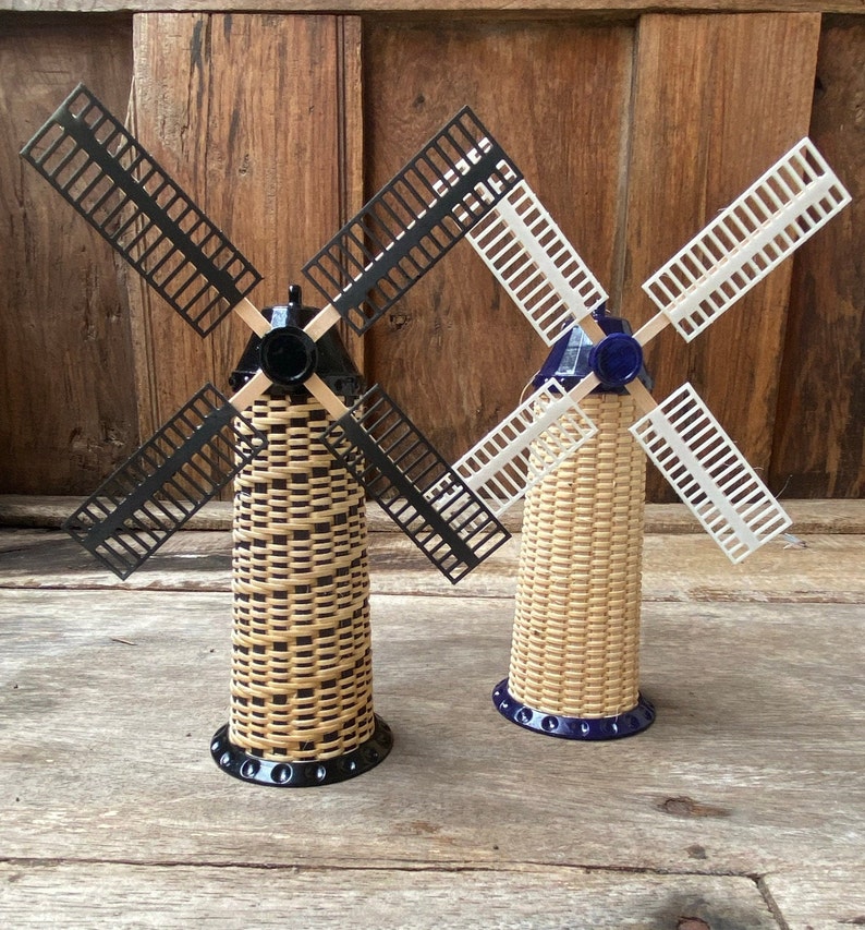 May include: Two miniature windmills with black and white blades. The windmills are made of woven wicker and have blue bases.
