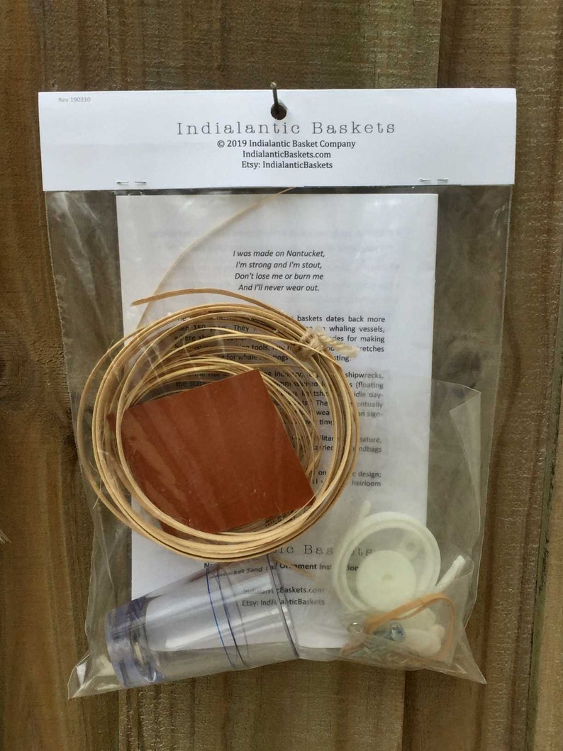 May include: A kit for making a small basket, containing a roll of natural reed, a small piece of brown leather, a clear plastic container, a white plastic ring, a rubber band, and a small metal hook. The kit comes with instructions and a poem about the history of Nantucket baskets.