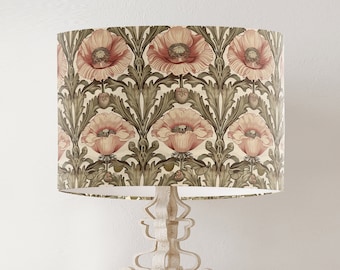 May include: A white lamp with a cream-colored lampshade featuring a floral pattern of pink poppies and green leaves.
