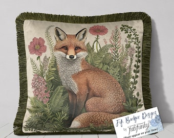 Può includere: Un cuscino decorativo con un bordo di frangia verde presenta un'illustrazione dipinta a mano di una volpe rossa seduta in una lussureggiante foresta verde con fiori rosa. Il cuscino è di colore crema con una texture sottile.