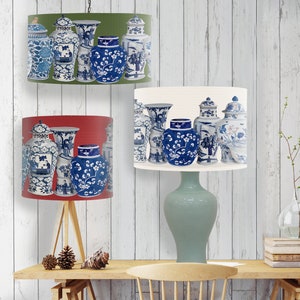May include: Three lampshades with a blue and white porcelain vase pattern. The lampshades are in red, white, and green. The lampshades are hanging from a ceiling fixture.