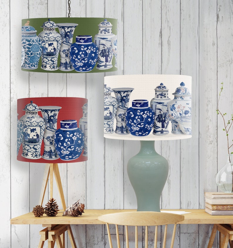 May include: Three lampshades with a blue and white porcelain vase pattern. The lampshades are in red, white, and green. The lampshades are hanging from a ceiling fixture.