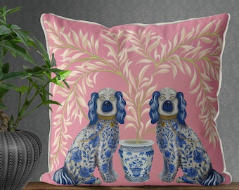 May include: A pink throw pillow with a floral design featuring two blue and white porcelain dogs flanking a blue and white porcelain vase with a floral design.