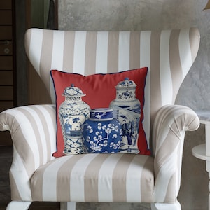 Könnte beinhalten: Ein rotes Kissen mit einem weißen und blauen Design aus drei chinesischen Ingwervasen. Die Ingwervasen sind mit floralen und geometrischen Mustern verziert.