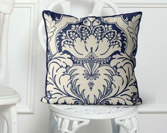 May include: A navy blue and cream throw pillow with a damask pattern. The pillow is sitting on a white chair.