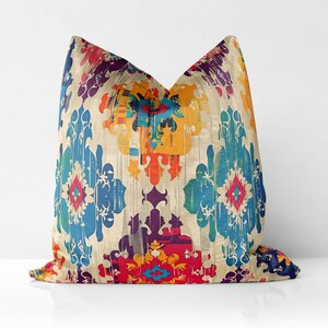 May include: A decorative throw pillow with a colorful geometric pattern in shades of blue, red, yellow, orange, and purple. The pattern is reminiscent of traditional ikat designs.