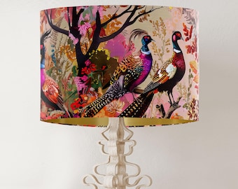 May include: A lampshade with a pink and gold background featuring a colorful illustration of three pheasants in a forest setting.