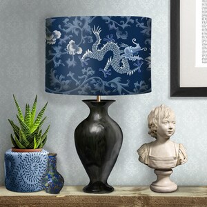 May include: A black table lamp with a blue and white patterned lampshade featuring a dragon design. The lampshade has a floral pattern with a blue background and white dragon.