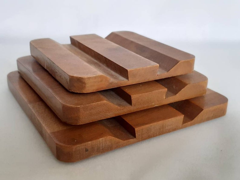 Puede incluir: Una pila de cuatro jaboneras de madera, cada una de un tama&ntilde;o diferente, en un tono marr&oacute;n c&aacute;lido. Las jaboneras tienen forma rectangular con un borde curvo y un dise&ntilde;o ranurado para el drenaje. La disposici&oacute;n crea un efecto escalonado.