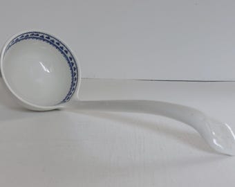 Może przedstawiać: Biała ceramiczna chochla z długim, zakrzywionym uchwytem. Miska ma niebiesko-biały kwiatowy wzór wokół krawędzi. Chochla jest przeznaczona do serwowania zup i gulaszu.