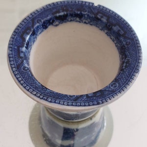 May include: A blue and white ceramic vase with a detailed pattern around the rim. The vase has a wide opening and a pedestal base. The design features a classic blue and white color scheme, with intricate patterns.
