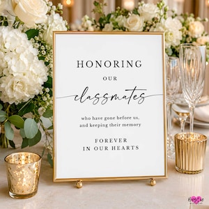 May include: A rectangular sign in a gold frame with white background and black text that reads: HONORING OUR classmates who have gone before us, and keeping their memory FOREVER IN OUR HEARTS. The sign is displayed on a flat surface.