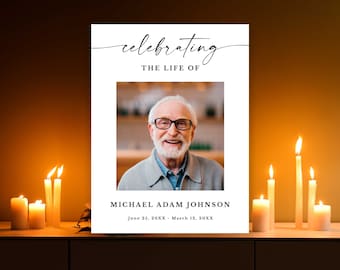 May include: A memorial sign with the text "celebrating the life of" above a photo of a smiling older man wearing glasses. The sign also includes the name "Michael Adam Johnson" and dates. Lit candles are in the foreground.