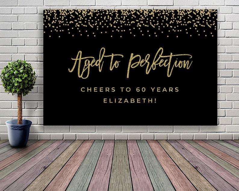 May include: Black banner with gold text and confetti. The text reads "Aged to perfection", "Cheers to 60 years", and "Elizabeth!". The banner is likely for a 60th birthday celebration.