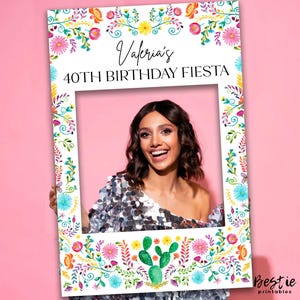 May include: A white photo booth frame decorated with vibrant floral and cactus patterns. The frame displays the text "Valeria's 40th Birthday Fiesta". A woman smiles within the frame against a pink backdrop. The Bestie printables logo is visible.