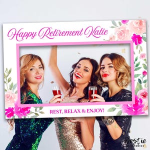 Puede incluir: Un marco de cabina de fotos rosa y blanco con diseños florales y el texto "Happy Retirement Katie" y "Rest, Relax & Enjoy!" El marco está decorado con flores rosas y blancas y hojas verdes.