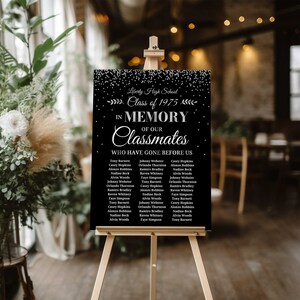 May include: Black and white sign with a silver glitter background. The sign reads "Liberty High School Class of 1975 In Memory of Our Classmates Who Have Gone Before Us" and lists the names of classmates.