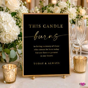 May include: A rectangular black sign in a gold frame with gold text that reads: THIS CANDLE burns in loving memory of those who cannot be here today but are forever present in our hearts TODAY & ALWAYS. The sign is displayed on a table.