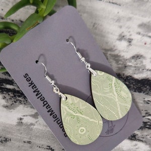 May include: A pair of green and white patterned teardrop-shaped earrings with silver hooks. The earrings are on a grey card with the text "BonnieMakes" printed on it.