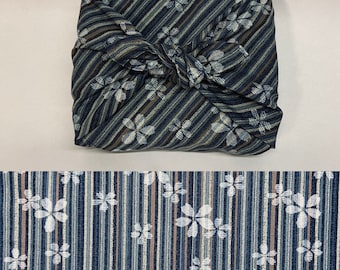 Furoshiki van Japans bedrukt katoen met een strepen- en bloemenpatroon op een marineblauwe achtergrond, verkrijgbaar in verschillende maten.
