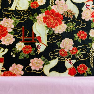 May include: A black fabric with a repeating pattern of white foxes, red and pink flowers, and gold accents. The foxes wear red collars. The bottom of the image shows a solid pink fabric.