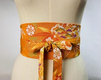 Reversible and adjustable obi belt in Japanese printed cotton with a bamboo and flower motif on an orange background. Solid orange or black side.