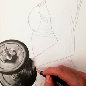 May include: A close-up of a hand drawing a black and silver dumbbell with a pencil. The dumbbell is in the foreground and the hand is in the background.