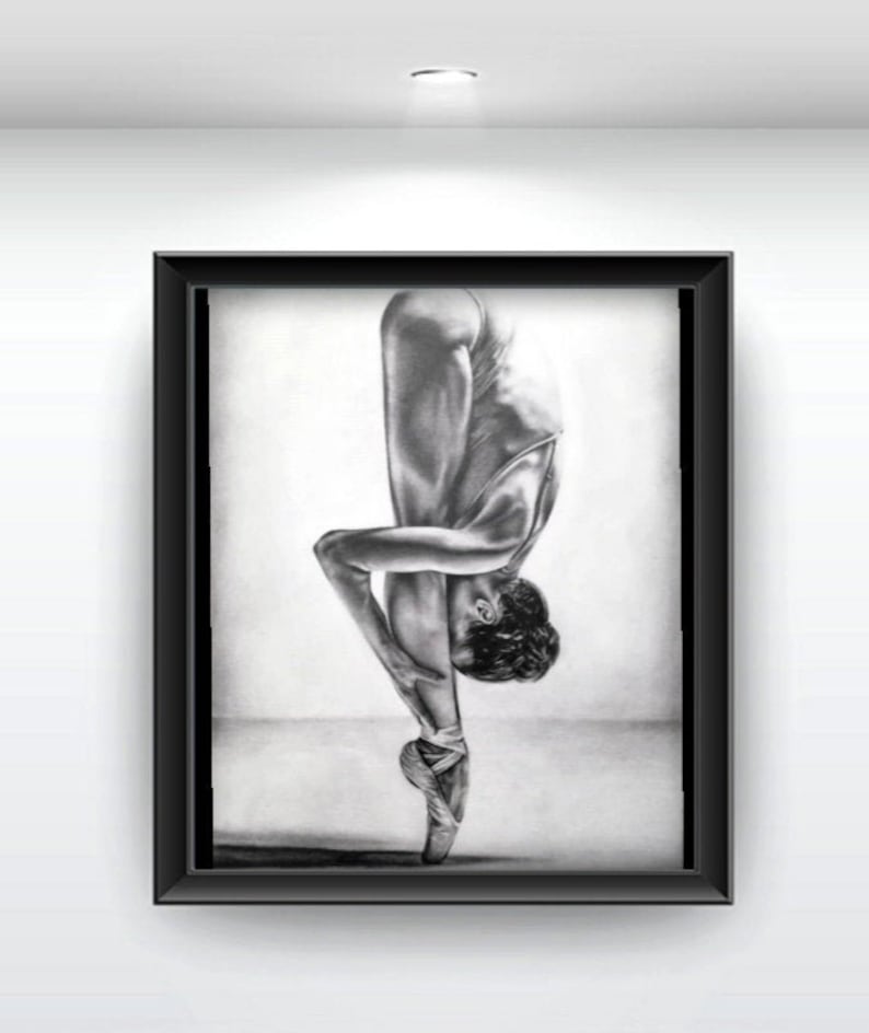 May include: A black and white pencil drawing of a ballerina in a pointe shoe pose. The ballerina is wearing a leotard and pointe shoes. The drawing is framed in a black frame.