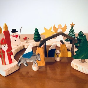 Könnte beinhalten: Ein hölzerner Adventskalender mit einer Weihnachtskrippe, einem Schneemann, einem Stern, Kerzen und Bäumen. Der Kalender ist aus hellem Holz gefertigt und in leuchtenden Farben bemalt.