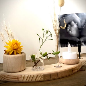 Può includere: Un vassoio di legno a forma di mezzaluna con tre piccoli vasi e un portacandele. I vasi contengono fiori secchi e un piccolo mazzo di fiori bianchi. Il portacandele è in legno e ha una candela bianca all'interno.