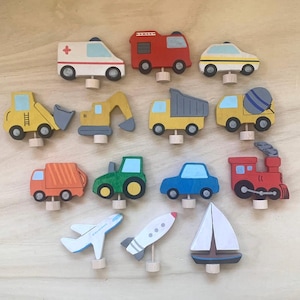 May include: A set of 15 wooden toy vehicles, including a fire truck, ambulance, dump truck, cement mixer, excavator, tractor, car, train, airplane, rocket, and sailboat. The toys are painted in bright colors and have simple, child-friendly designs.