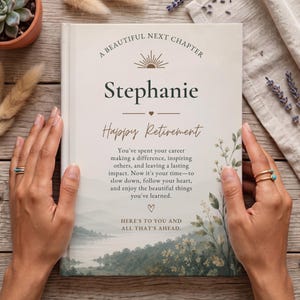 Puede incluir: Un libro de tapa dura con una cubierta de color crema que presenta el texto A BEAUTIFUL NEXT CHAPTER, Stephanie, Happy Retirement y un mensaje sobre la jubilaci&oacute;n. La cubierta incluye un icono de sol, un coraz&oacute;n y una ilustraci&oacute;n paisaj&iacute;stica.