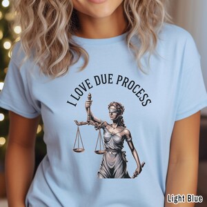 May include: Light blue t-shirt with the text "I LOVE DUE PROCESS" above an illustration of Lady Justice holding scales. The graphic is in black and white. The words "Light Blue" are at the bottom right.