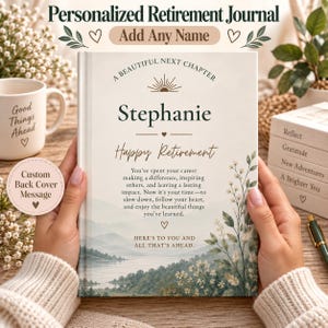 May include: A personalized retirement journal with a cream-colored cover featuring a landscape illustration of a lake and mountains. The text reads A Beautiful Next Chapter, Stephanie, Happy Retirement, and a message about career impact.