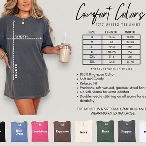 May include: A woman wearing a dark gray Comfort Colors 1717 unisex tee shirt. The image includes a size chart with measurements in inches, and color options: black, blue jean, crunchberry, espresso, ivory, moss, pepper, and white.