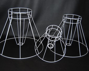 May include: Three white metal lampshade frames of different sizes. The frames are cone-shaped and have a circular base.