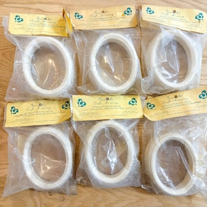 May include: Six oval craft accessory hoops in clear plastic packaging with yellow labels. The labels read "Jean Art Craft Accessory". The hoops are white and appear to be made of wood or a similar material. The packaging is sealed.