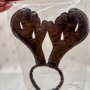 May include: Brown reindeer antler headband in a clear plastic package. The antlers are made of a soft, plush material and are attached to a dark brown headband. The packaging reads "One Size Fits All".